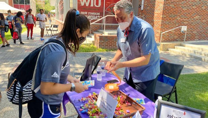 Students at a hand out table in the UIW quad